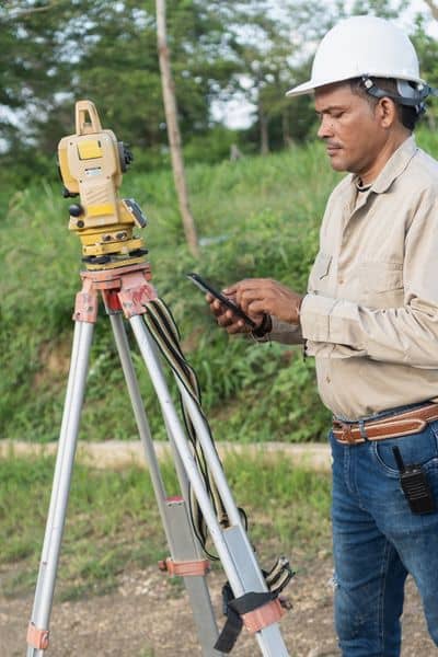 Licensed land surveyor using GPS equipment to accurately locate property lines on a residential lot